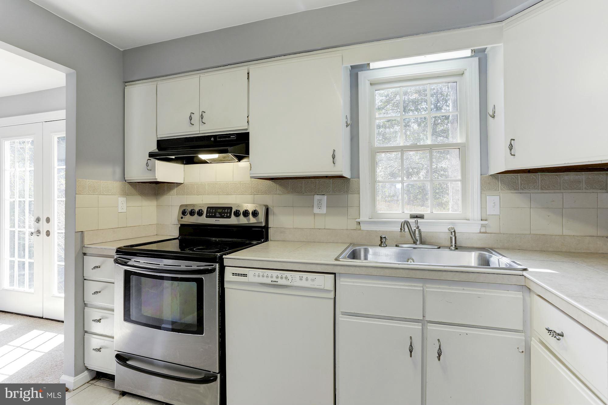 6023 Maple Road St. Leonard, MD 20685 - Photo 9 of 30 a kitchen with granite countertop white cabinets appliances and a window