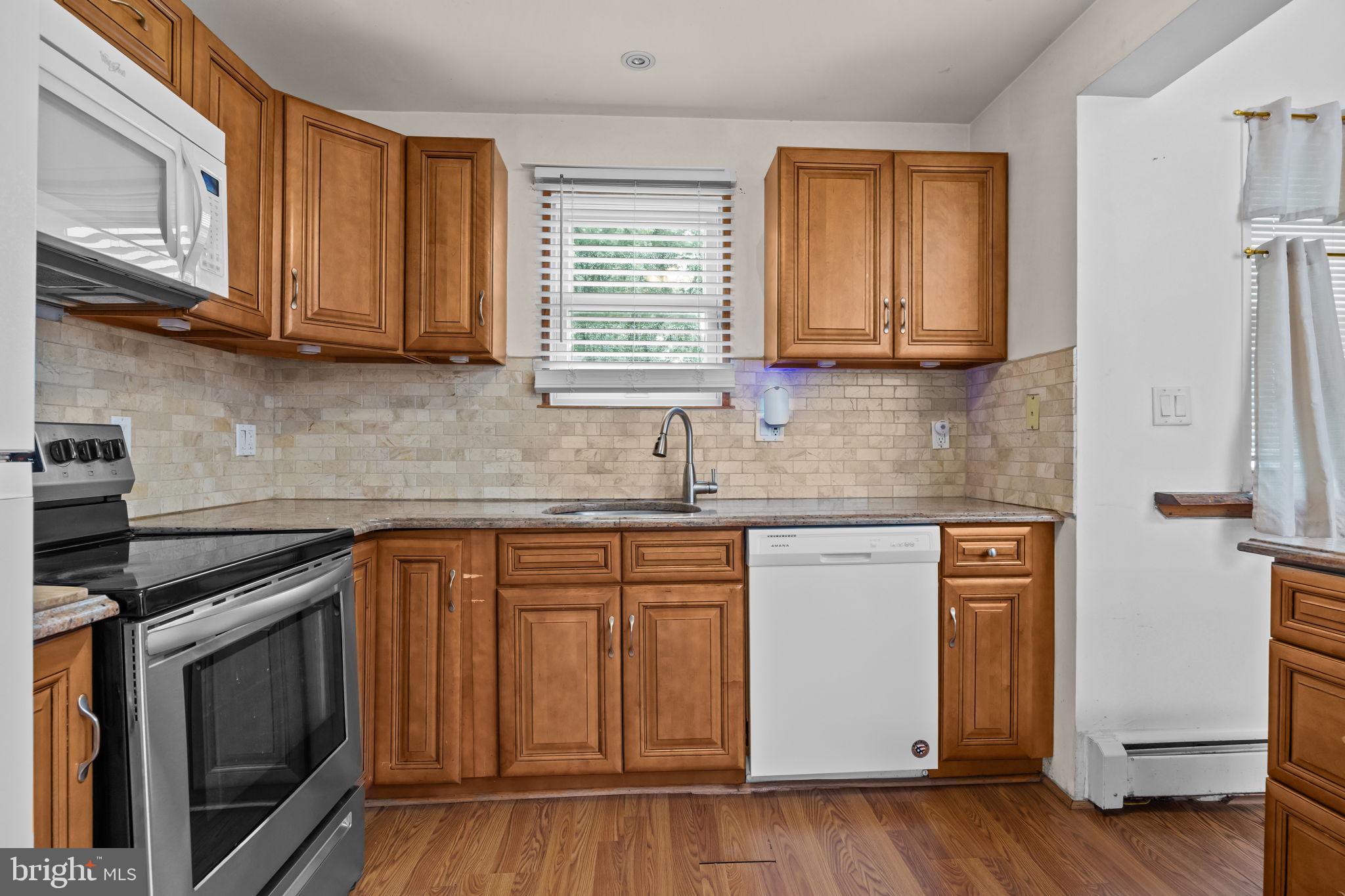 36 Grapevine Road Levittown, PA 19057 - Photo 7 of 19 a kitchen with stainless steel appliances granite countertop a sink a stove cabinets and wooden floor