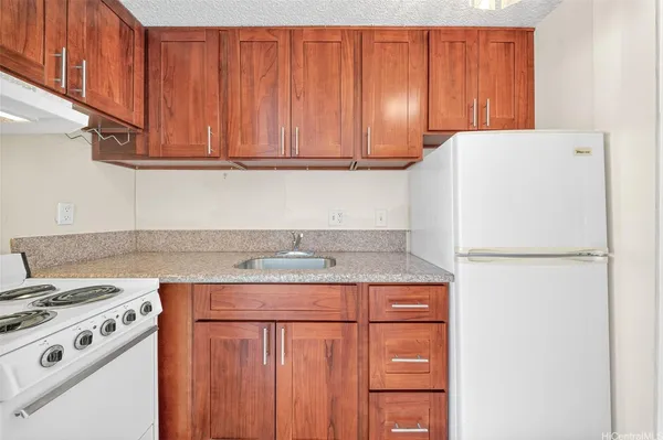 a kitchen with granite countertop a sink a stove and cabinets