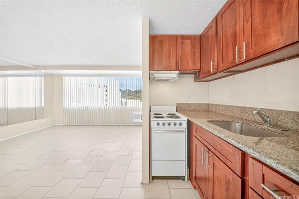 a kitchen with granite countertop a sink a stove and cabinets