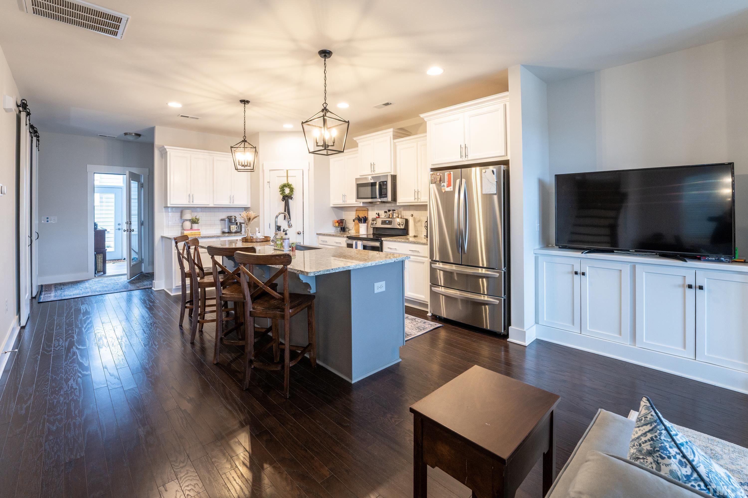 272 Daniel Ridge Road Wendell, NC 27591 - Photo 15 of 39 a kitchen with stainless steel appliances a dining table chairs wooden floor and a refrigerator