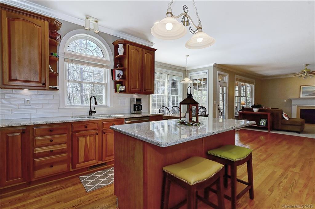 3203 Planters Ridge Road Charlotte, NC 28270 - Photo 5 of 36 a kitchen with stainless steel appliances granite countertop a sink dishwasher and a flat tv screen next to a large window with wooden floor