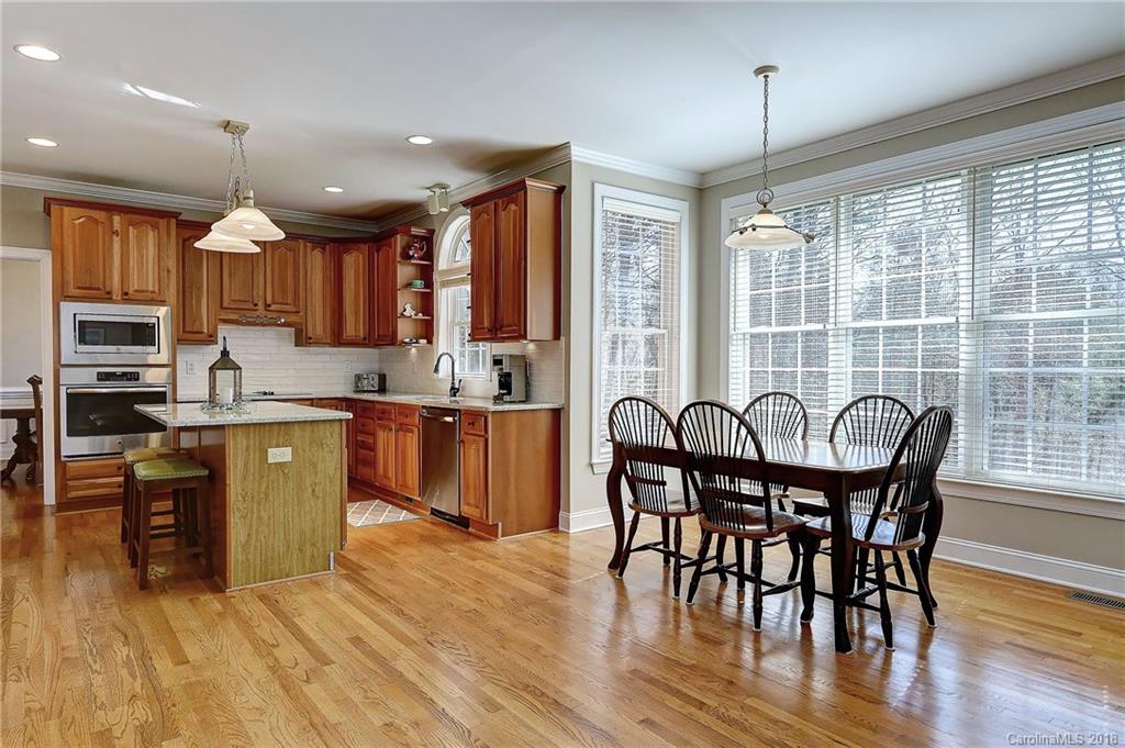 3203 Planters Ridge Road Charlotte, NC 28270 - Photo 7 of 36 a kitchen with stainless steel appliances granite countertop wooden floor a dining table and chairs