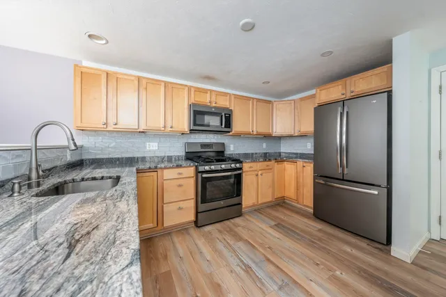 a kitchen with granite countertop a refrigerator stove and sink