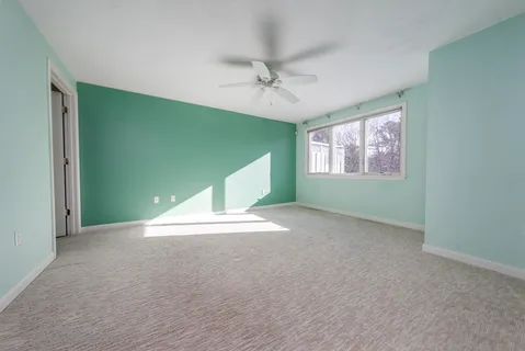 an empty room with windows and ceiling fan