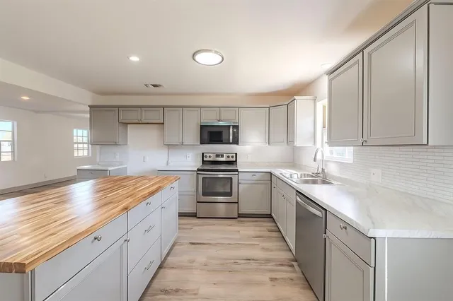 a kitchen with granite countertop a sink stainless steel appliances and cabinets
