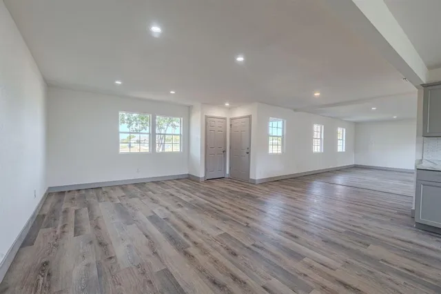 a view of an empty room with wooden floor and window