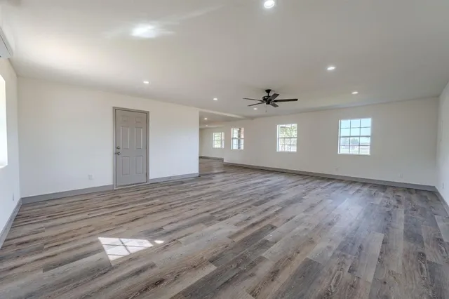 a view of empty room with window and wooden floor
