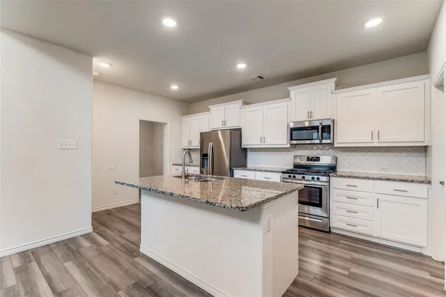 a kitchen with stainless steel appliances granite countertop a stove a sink and a refrigerator