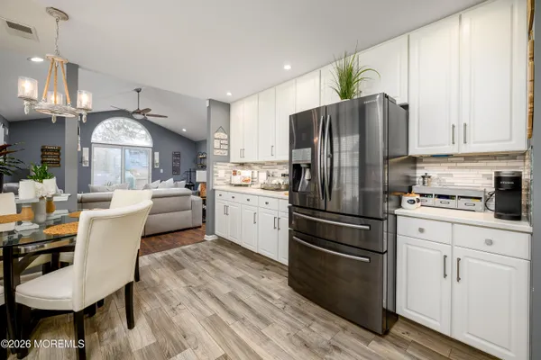 a kitchen with a refrigerator a stove a sink and white cabinets with wooden floor