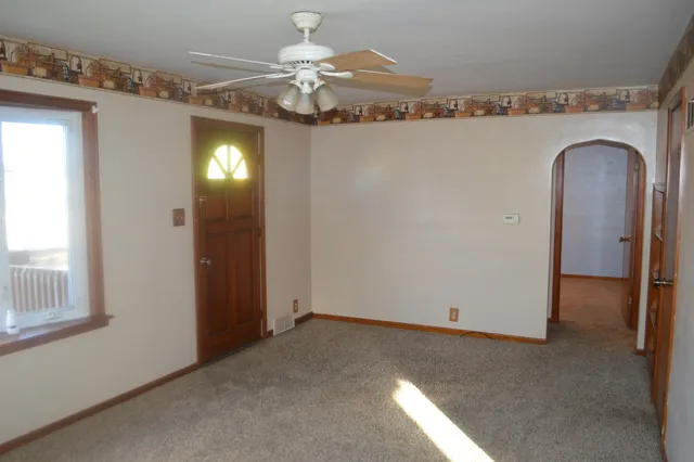 a view of a livingroom with a chandelier fan and windows