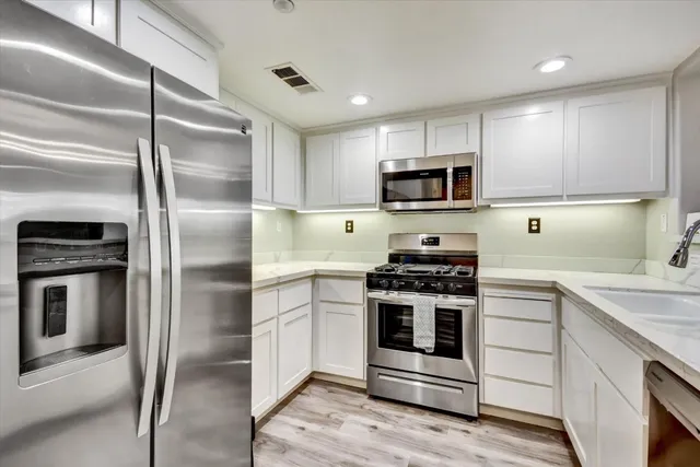 a kitchen with cabinets stainless steel appliances and wooden floor