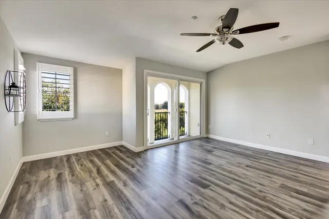 a view of an empty room with a window and wooden floor