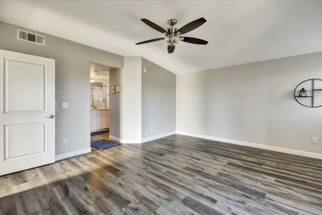an empty room with wooden floor and windows