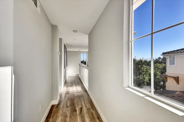 a view of a hallway with wooden floor and a living room