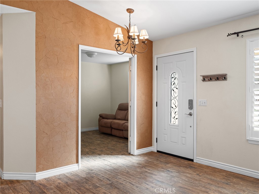 16986 Ocotilla Road Apple Valley, CA 92307 - Photo 4 of 39 a view of a livingroom with hallway chandelier and wooden floor