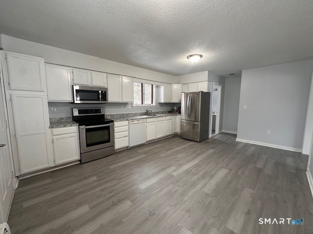 259 Westchester Road, Unit A Colchester, CT 06415 - Photo 4 of 22 a kitchen with refrigerator a microwave oven and a sink with wooden floor