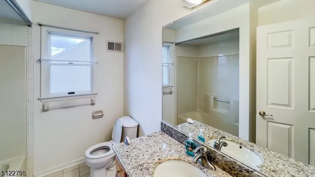 a bathroom with a granite countertop sink toilet a mirror and shower