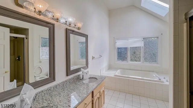 a spacious bathroom with a granite countertop tub sink and mirror
