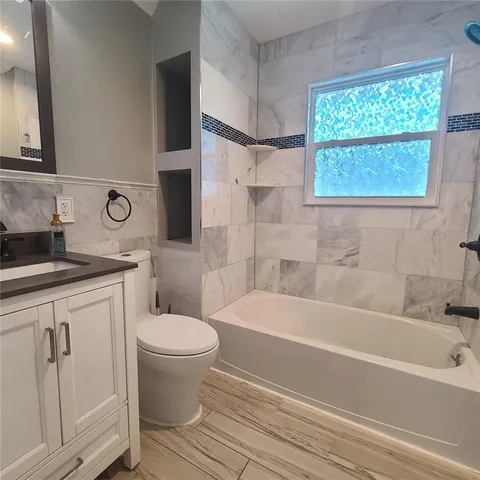a bathroom with a granite countertop toilet a sink and a bathtub