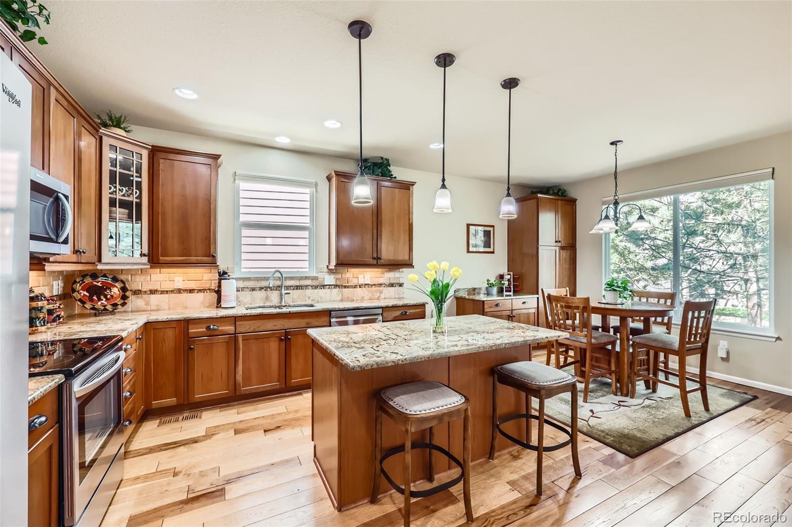 2872 Dreamcatcher Loop Castle Rock, CO 80109 - Photo 11 of 42 a kitchen with stainless steel appliances granite countertop a stove a sink a dining table chairs and view of living room