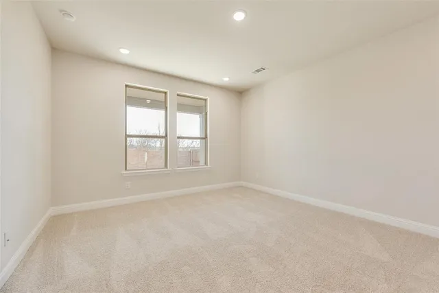 an empty room with windows and view of kitchen