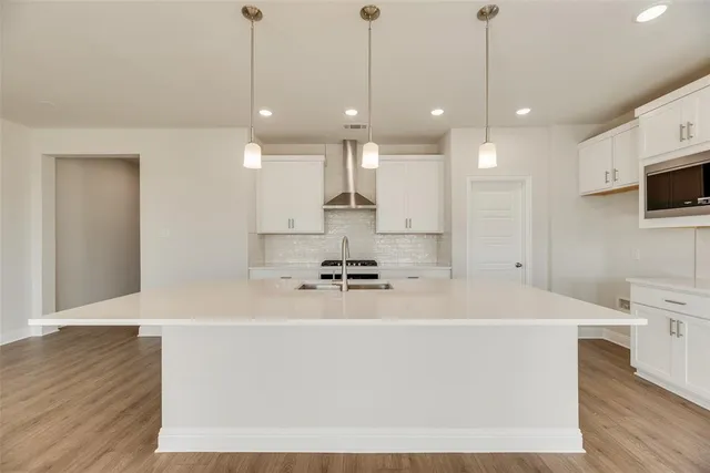 a large kitchen with kitchen island a stove a sink a center island and wooden floor