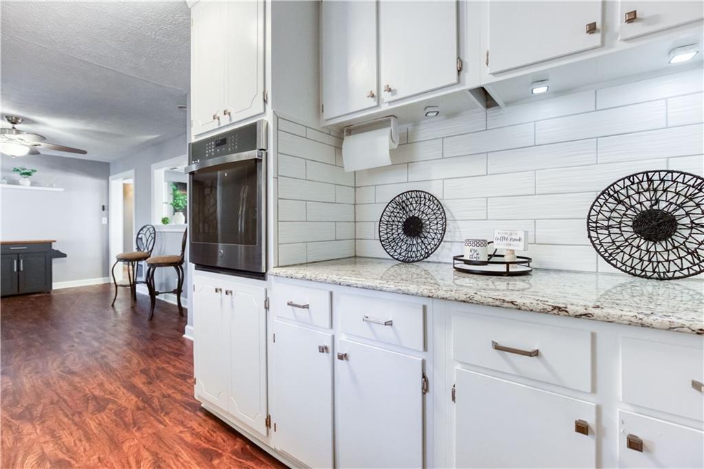 23 Woodland Road Auburn, GA 30011 - Photo 14 of 34 a kitchen with granite countertop white cabinets and wooden floor