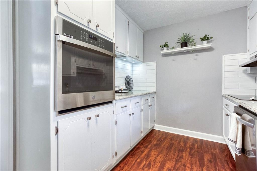 23 Woodland Road Auburn, GA 30011 - Photo 16 of 34 a kitchen with granite countertop white cabinets and white appliances