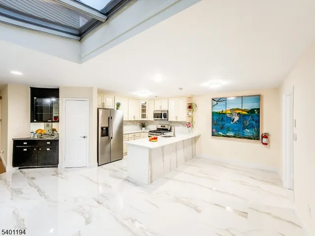 a kitchen with stainless steel appliances granite countertop a refrigerator a stove a sink a dining table and chairs with wooden floor