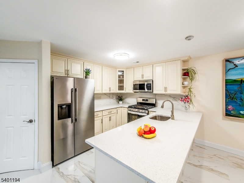7B Rutland Lane Monroe Township, NJ 08831 - Photo 20 of 36 a kitchen with stainless steel appliances granite countertop a refrigerator a stove a sink a dining table and chairs with wooden floor