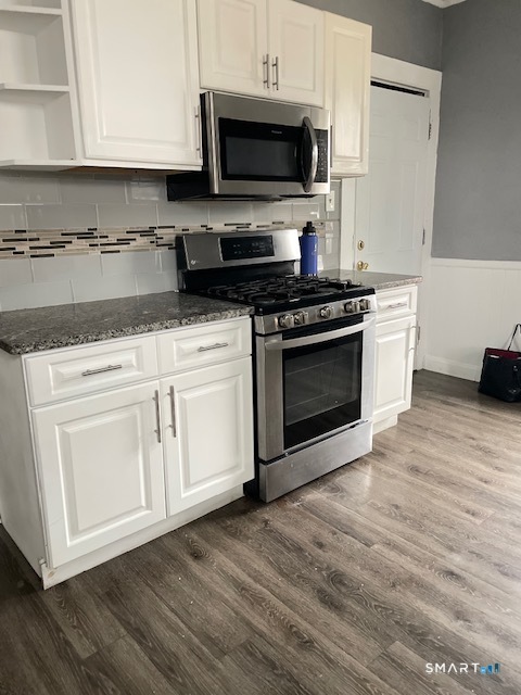 a kitchen with stainless steel appliances granite countertop a stove a microwave and a white cabinets