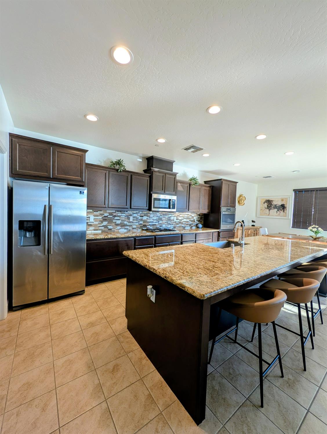 174 Emperor Way Dinuba, CA 93618 - Photo 3 of 23 a kitchen with stainless steel appliances granite countertop a table chairs sink and refrigerator