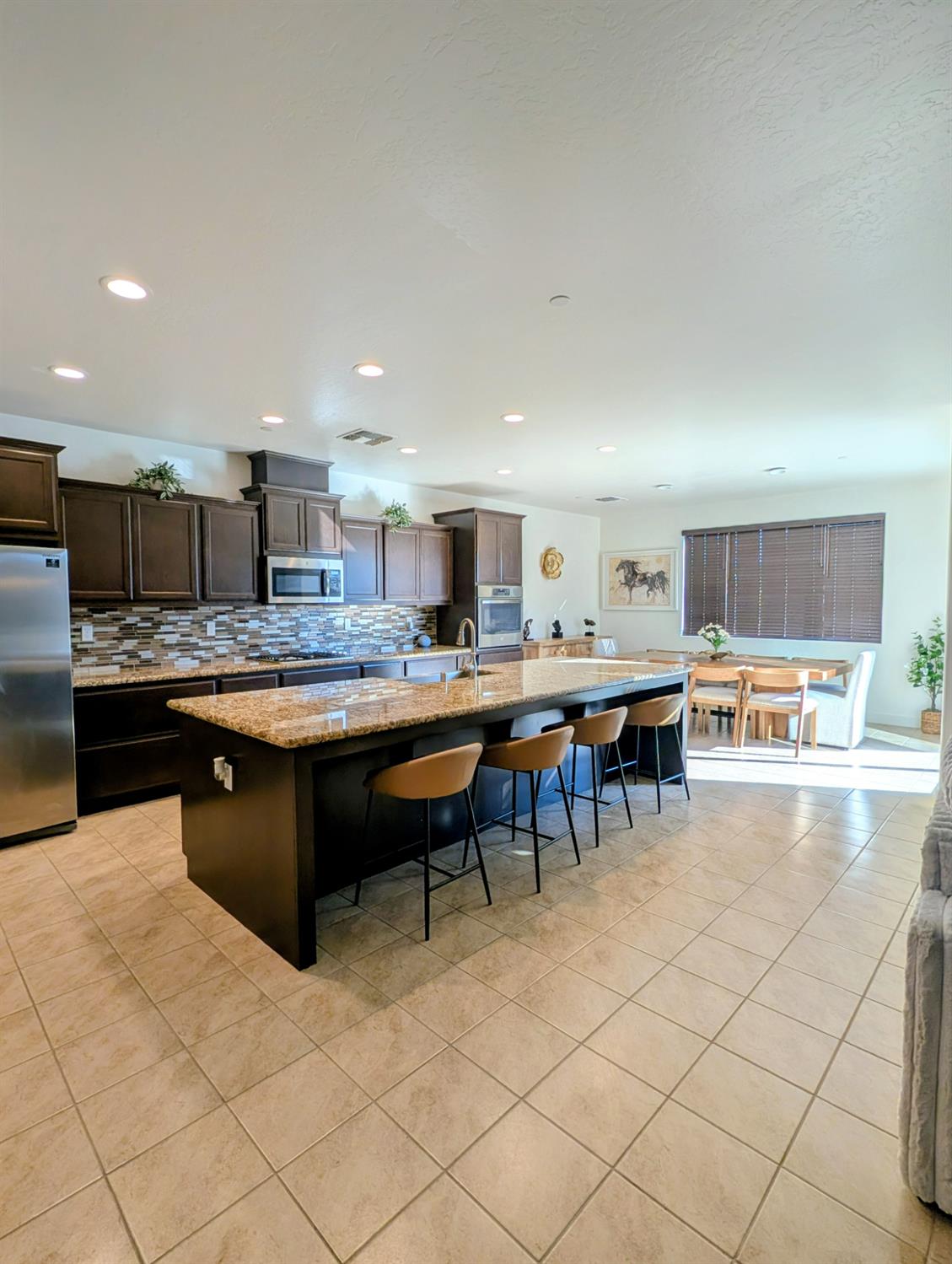 174 Emperor Way Dinuba, CA 93618 - Photo 5 of 23 a kitchen with stainless steel appliances kitchen island granite countertop a sink and cabinets