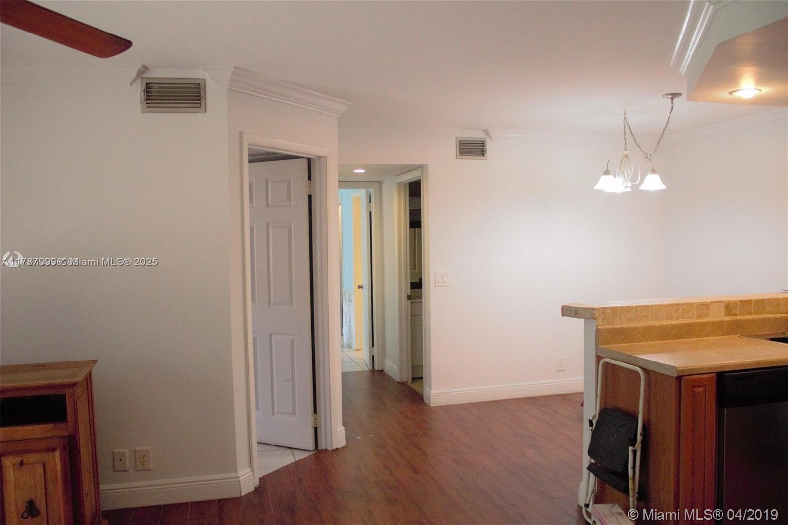 545 Trace Circle, Unit 110 Deerfield Beach, FL 33441 - Photo 11 of 20 a view of a room with wooden floor and chandelier