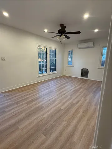 an empty room with wooden floor ceiling fan and windows
