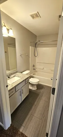 a bathroom with a granite countertop sink mirror vanity and toilet