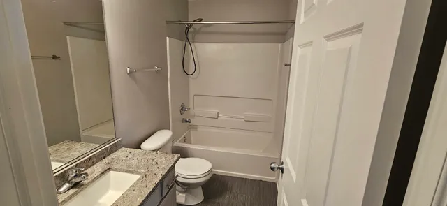 a bathroom with a granite countertop toilet a sink and shower