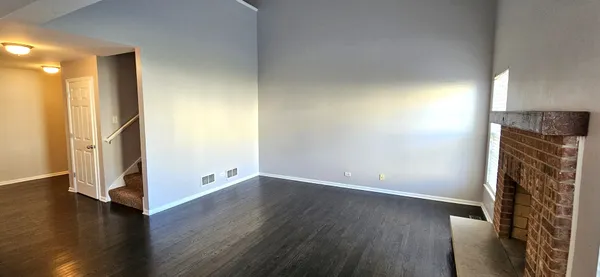 an empty room with wooden floor and a fireplace