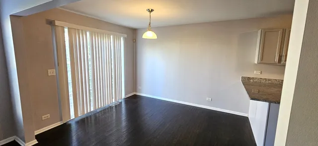 an empty room with wooden floor windows and entrance