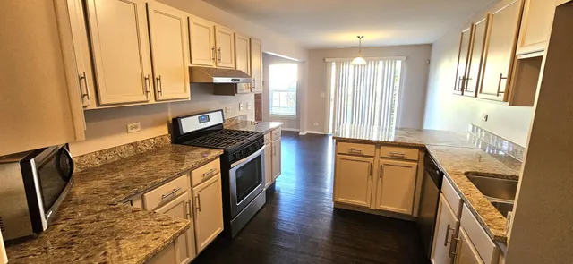 a kitchen with stainless steel appliances granite countertop a stove a sink and a refrigerator