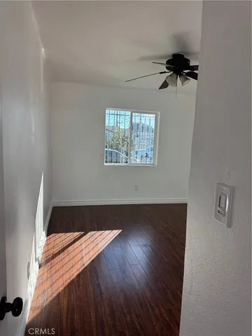 an empty room with wooden floor fan and windows