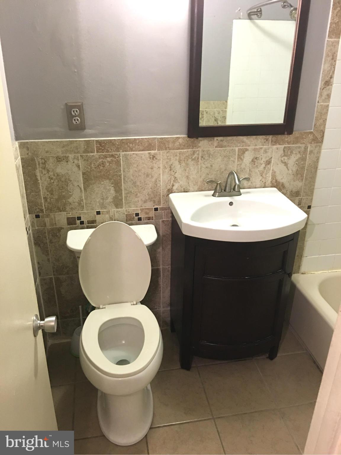 9270 Adelphi Road, Unit 103 Hyattsville, MD 20783 - Photo 12 of 14 a bathroom with a sink a toilet and a mirror