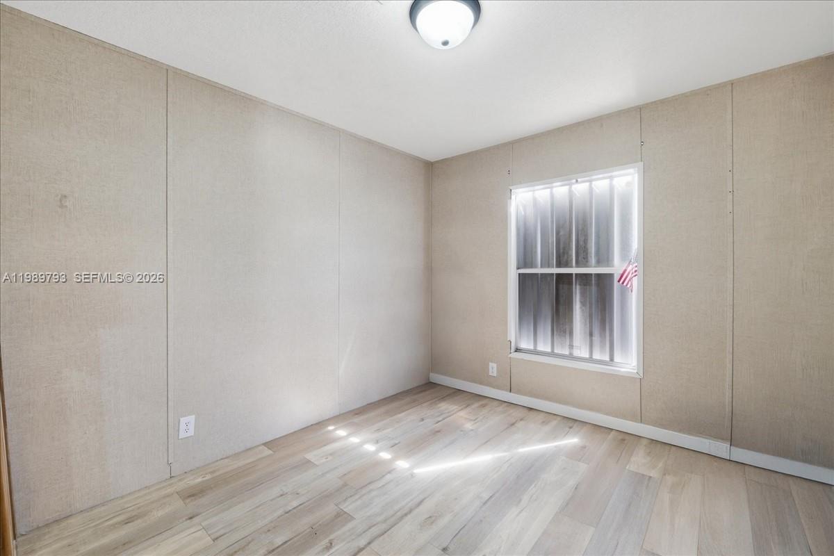 415 South Kennel Street Clewiston, FL 33440 - Photo 14 of 34 an empty room with wooden floor and windows