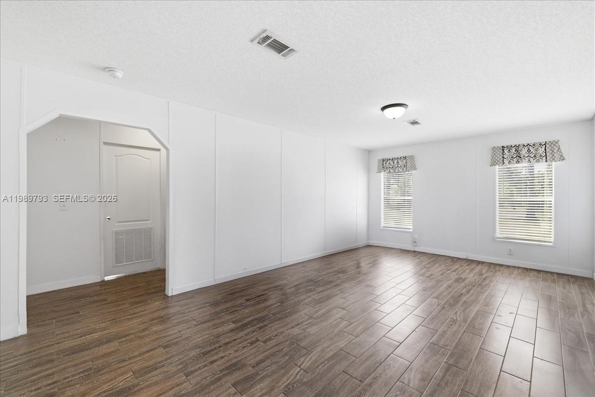 415 South Kennel Street Clewiston, FL 33440 - Photo 3 of 34 an empty room with wooden floor and windows