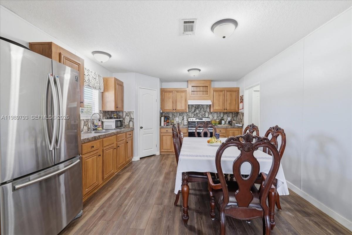 415 South Kennel Street Clewiston, FL 33440 - Photo 7 of 34 a kitchen with stainless steel appliances granite countertop a dining table chairs refrigerator and cabinets