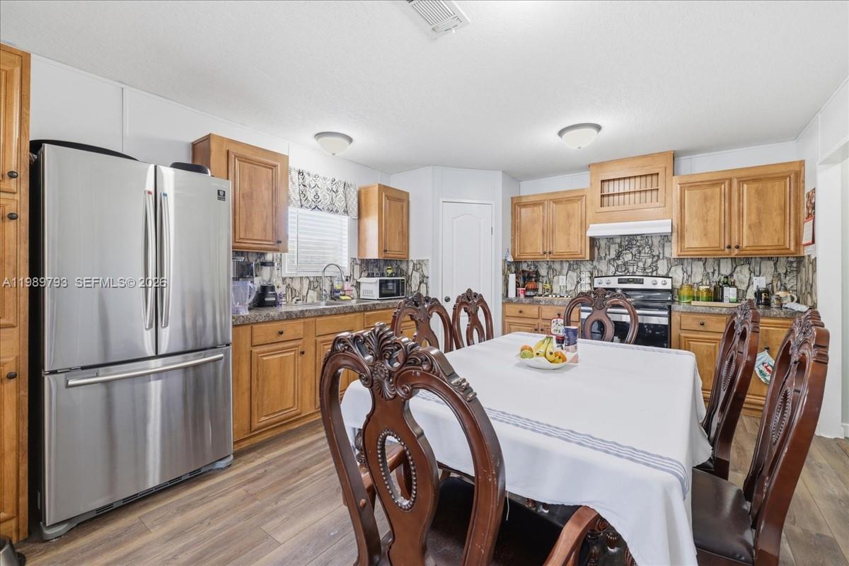 415 South Kennel Street Clewiston, FL 33440 - Photo 8 of 34 a kitchen with stainless steel appliances a refrigerator a sink a stove a dining table and chairs