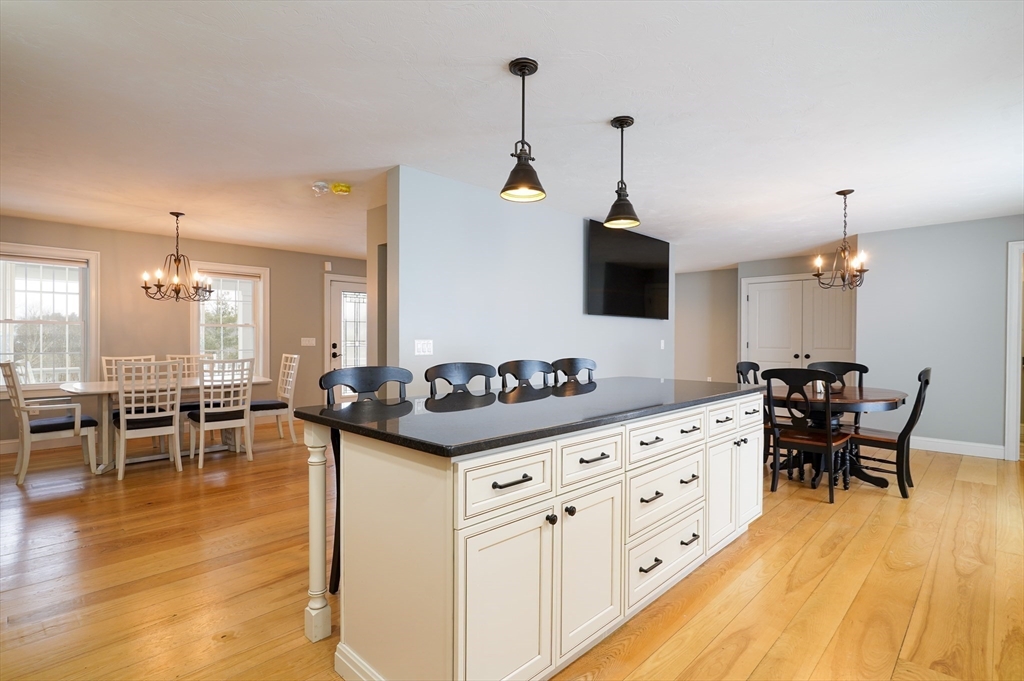 162 Fiskdale Road Brookfield, MA 01506 - Photo 7 of 42 a kitchen with granite countertop a stove a sink a dining table and chairs with wooden floor