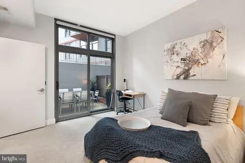 a bedroom with a bed and a table with painting on the wall