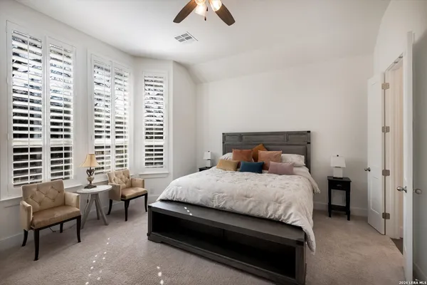 a bedroom with a bed a couch and a chandelier fan